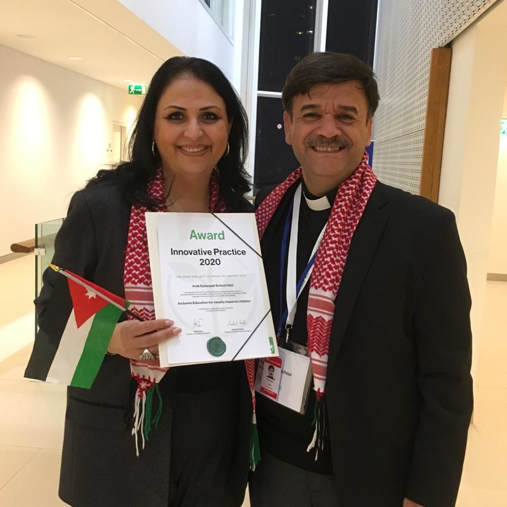 Pfr. Samir Esaid und seine Frau, Schulleiterin Sabah Zurikat, freuen sich und halten die Gewinnerurkunde und eine jordanische Flagge ins Bild.